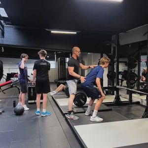 Ulf Berg instruerar en ung idrottare i knäböj/utfall med skivstång i gymmet – fysträning för lag och föreningar